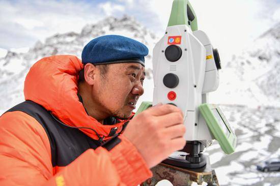 自然资源部第一大地测量队队员郑林在使用全站仪对珠峰峰顶进行交会观测（5月27日摄）。新华社记者孙非摄