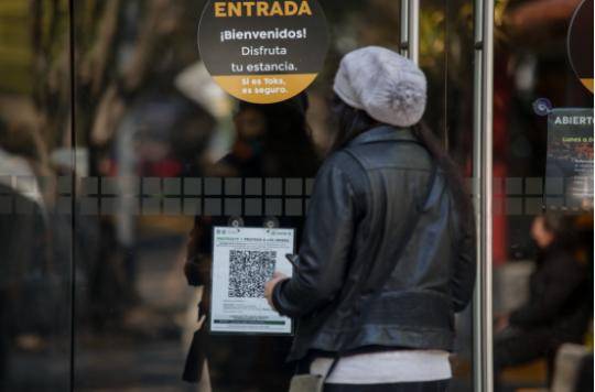 12月8日，在墨西哥首都墨西哥城，一名路人在一家餐馆门口用手机扫二维码。（弗朗西斯科·卡涅多摄）