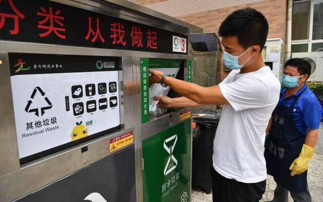 7月30日，东城区新世界家园，居民将一袋厨余垃圾投入装有破袋器的垃圾桶。破袋器会打破塑料袋，倾倒垃圾，再将塑料袋转入其他垃圾桶。摄影/新京报记者吴江