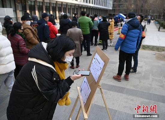 12月26日，根据新冠肺炎疫情防控要求，北京市朝阳区望京地区望京街道、东湖街道开展为期两天的社区全员核酸检测。图为一位居民在望京街道一处小区内的采样点查看预约采样流程。中新社记者侯宇摄