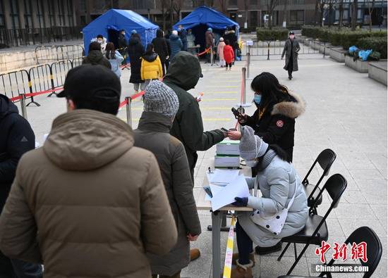 12月26日，根据新冠肺炎疫情防控要求，北京市朝阳区望京地区望京街道、东湖街道开展为期两天的社区全员核酸检测。图为望京街道一处居民小区内的采样点，工作人员对居民进行采样信息登记确认。中新社记者侯宇摄