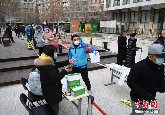 12月26日，根据新冠肺炎疫情防控要求，北京市朝阳区望京地区望京街道、东湖街道开展为期两天的社区全员核酸检测。图为望京街道一处居民小区内的采样点，工作人员引导居民进行采样。中新社记者侯宇摄