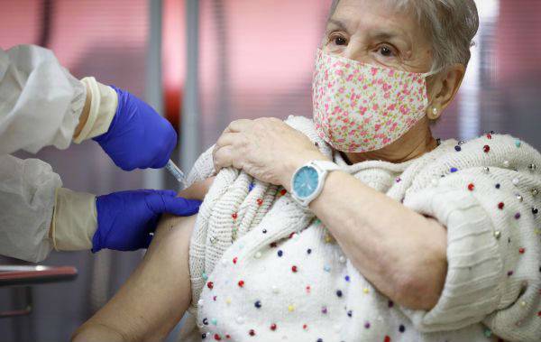 27日，西班牙马德里一位老妇人正接受疫苗接种。（路透社）