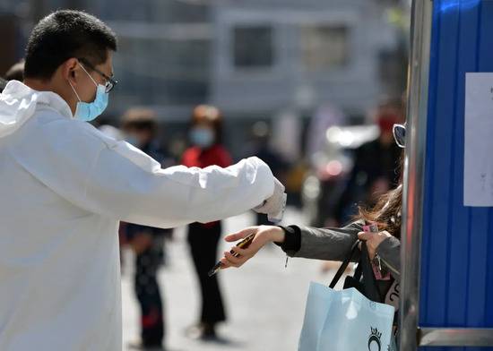 在武汉市武昌楚材社区，工作人员为出入者测体温
