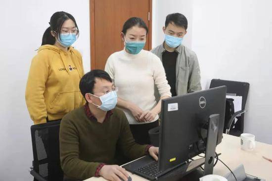 王小莉（后排中二）正在和同事们分析感染者分布特点。新京报记者王嘉宁摄