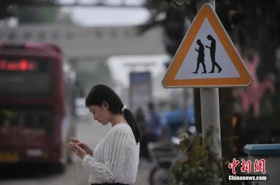 资料图：重庆涪陵红酒小镇一红绿灯处摆放警示牌，提醒市民在过斑马线的时候不能玩手机。陈超摄