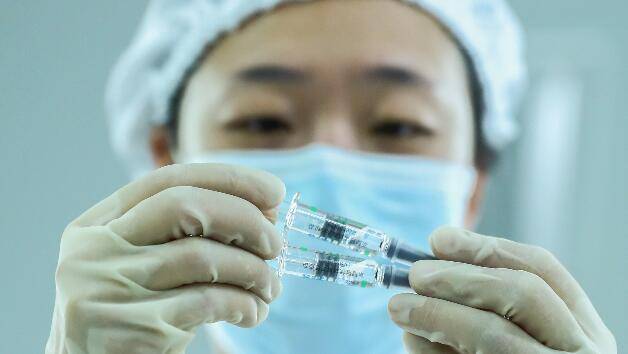 12月25日，工作人员在国药集团中国生物北京生物制品研究所的新冠病毒灭活疫苗分包装车间内检查产品包装质量。新华社记者张玉薇摄