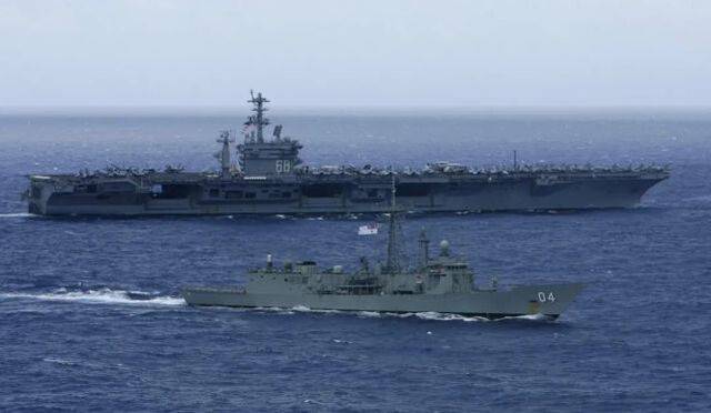 这是2012年7月18日，在美国夏威夷瓦胡岛以北海域，参加“环太平洋”军演的一艘澳大利亚海军舰只（前）和美国海军“尼米兹”号航母一同航行的资料照片。新华社/路透