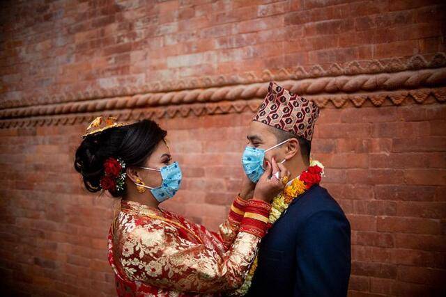 ↑2020年5月1日，在尼泊尔首都加德满都一场婚礼上，佩戴口罩的新人相互表达爱意。新华社发（苏拉韦·什雷斯塔摄）