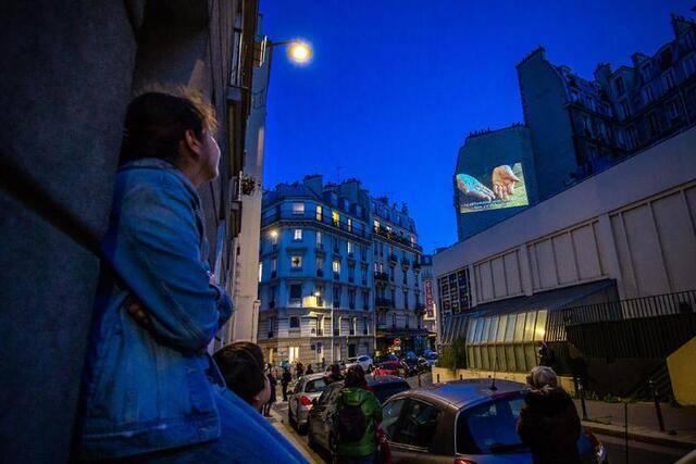 ↑2020年5月1日，法国巴黎一家电影院在街头墙壁上播放电影，供禁足在家的民众周末消遣，声援在新冠疫情中受到重创的电影业。新华社发（奥雷利安·莫里萨尔摄）