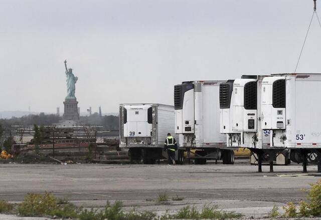 ↑2020年5月11日，冷藏拖车停放在美国纽约布鲁克林的临时停尸场所内。由于死亡病例激增导致停尸房已满，当地一些医院只能找冷藏车保存病患遗体。新华社记者王迎摄