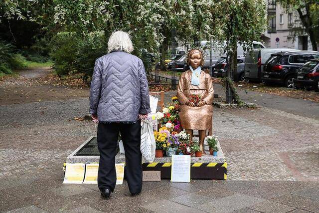 ↑2020年10月15日，在德国首都柏林，一名行人驻足观看“慰安妇”铜像。新华社记者单宇琦摄