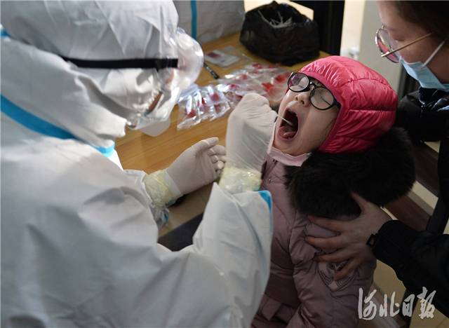 2021年1月6日，医务人员在河北省石家庄市香榭苑小区核酸检测点为居民进行核酸检测。河北日报记者张昊摄