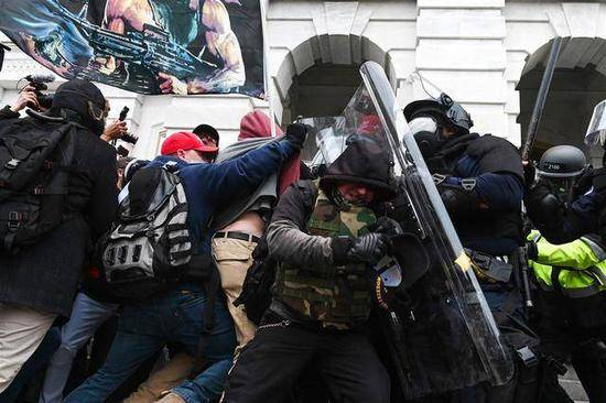 （图说：1月6日，国会警察在与冲击国会的暴徒对抗。图/AFP/Getty Images）