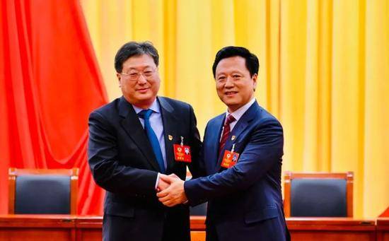 大会现场，原房山区政协主席刘兵（左）与新当选的房山区政协主席魏广勋握手。