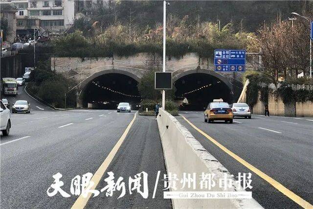 一位市民正在车流中翻过护栏横穿马路