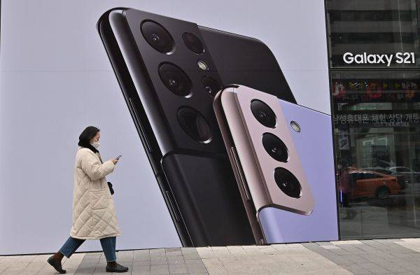 资料图片：1月28日，首尔街头一女子走过三星盖乐世S21智能手机的广告牌。（法新社）