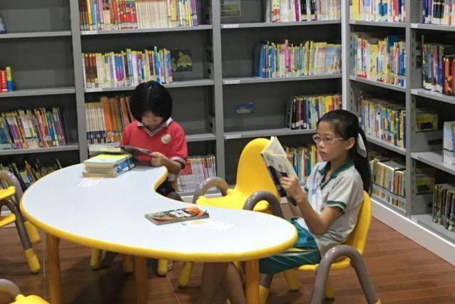 在社区图书馆看书的小微和小欣姐妹俩。