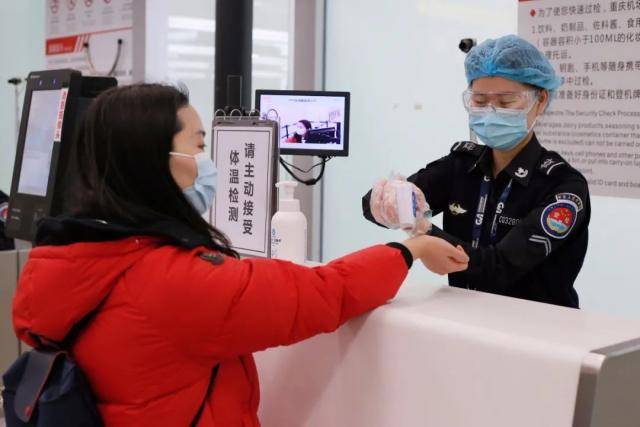 机场安检人员对每位旅客实施安全检查、测量体温。图：重庆江北机场