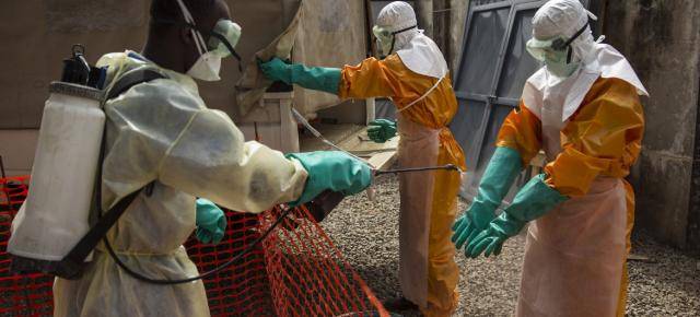△2015年，在几内亚科纳克里，红十字与红新月联会的一名工作人员将消毒氯溶液喷洒在一名工作人员戴着手套的手上。图片来源：联合国儿基会