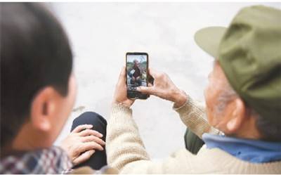 在湖南省湘西土家族苗族自治州芙蓉镇杨木村，“网红爷爷”彭国飞（右）向村民彭宏云展示自己的短视频。新华社记者薛宇舸摄