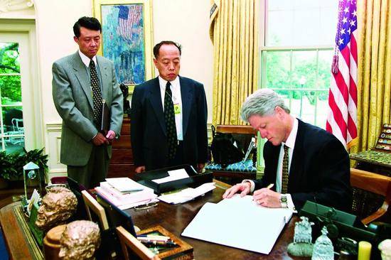 ·1999年，时任驻美大使李肇星（中）和时任驻美公使刘晓明（左）前往白宫交涉。时任美国总统克林顿就美国轰炸中国驻南联盟大使馆事件，写下哀悼遇难者的话。