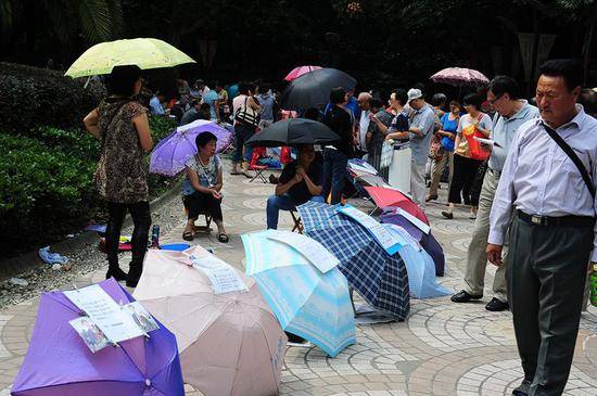  2014年9月27日，上海人民公园相亲角内人头攒动，父母将子女的征婚信息贴在雨伞上。