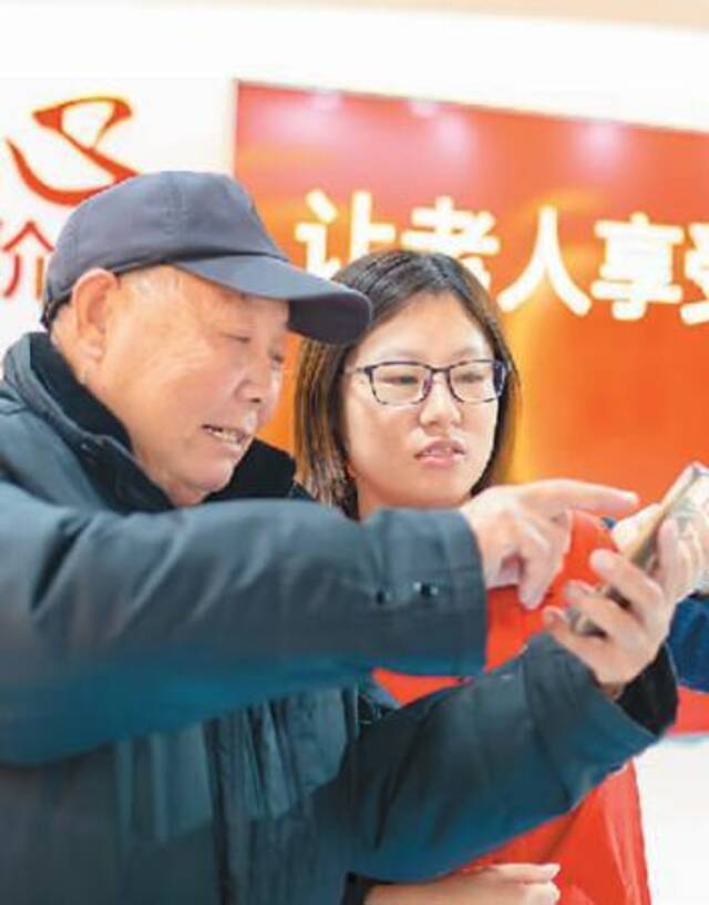 江苏省海安市育才社区的工作人员在给老人讲解如何使用智能手机。翟慧勇摄(人民图片)
