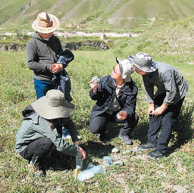 考察队员在通天河岸边研究石器