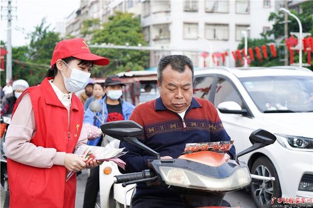 陆川县纪委监委干部向群众发送宣传单，普及交通法规知识，倡导安全出行、文明出行。（陆川县纪委监委供图）