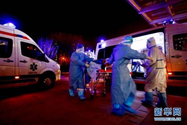 在武汉泰康同济医院接诊大厅外，军队支援湖北医疗队队员接收转运来的患者（2020年3月14日摄）。新华社发（王皓宇摄）