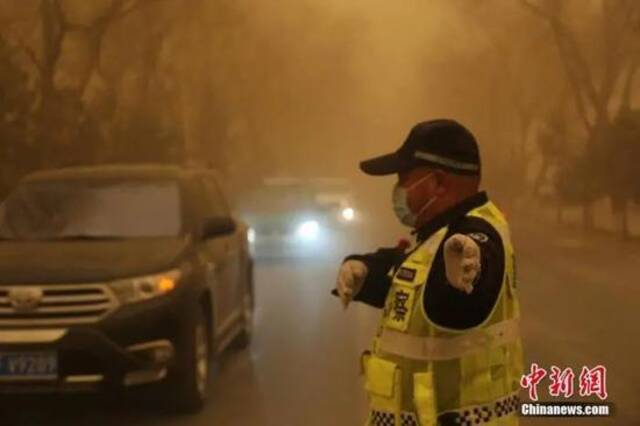 3月15日，甘肃多地遭遇沙尘天气，一名交警戴口罩执勤。胡广信摄