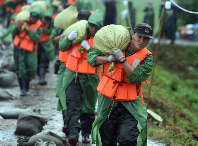 2020年7月16日，在安徽无为长江大堤外护圩三垄圩段，武警安徽总队芜湖支队的官兵在搬运沙袋，准备加固子埂。新华社记者周牧摄