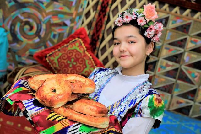 ↑一名身着民族服饰的哈萨克斯坦女孩在努尔苏丹展示传统美食。