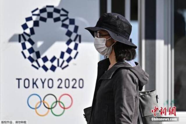 图为一名女士走过2020年东京奥运会海报。
