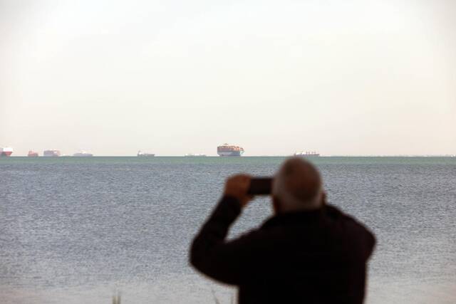 3月25日，在埃及伊斯梅利亚省大苦湖，一名男子拍摄等待通过苏伊士运河的船只。新华社发（艾哈迈德·戈马摄）