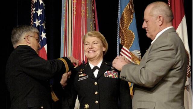2008年11月14日，在五角大楼举行的晋升仪式上，陆军参谋长乔治·W。凯西上将（左）和邓伍迪的丈夫克雷格·布罗奇（退役上校）为邓伍迪换上新肩章，她成为美国历史上第一位女性四星上将。（图源：美国陆军时报）
