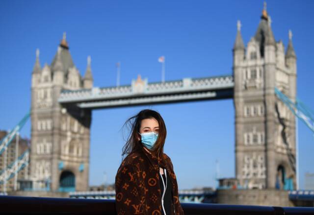 英国伦敦，一位女士戴着口罩在塔桥前拍照。（资料图）