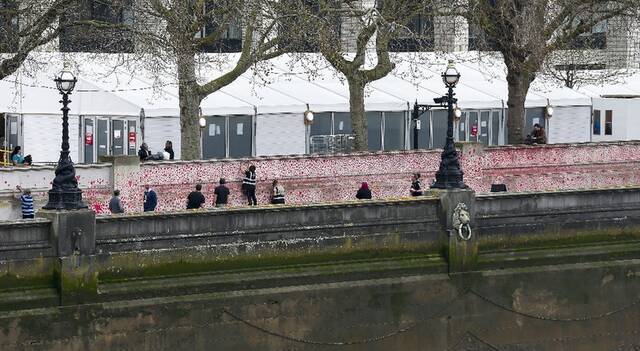 ↑志愿者在英国伦敦的国家新冠纪念墙上画红色的心