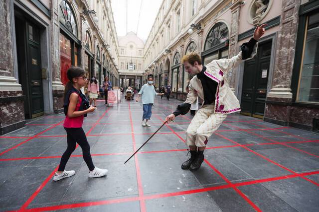 这是2020年7月15日，戏剧艺术家在比利时布鲁塞尔市中心与一名女孩互动“格子游戏”。此互动躲避游戏旨在提示人们在新冠疫情期间注意保持社交距离。新华社记者郑焕松摄