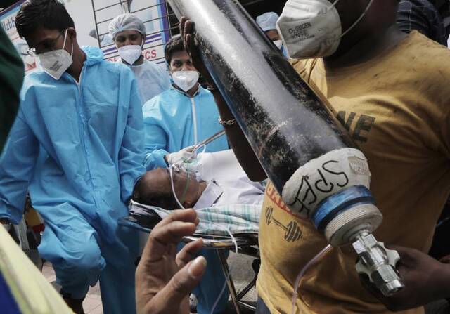 ▲一位病重的患者被送进医院，他的家人举着维持他呼吸的氧气瓶。图据NDTV