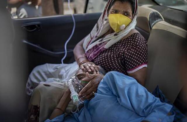 4月24日，在印度新德里，一名新冠患者在车内吸氧。新华社图