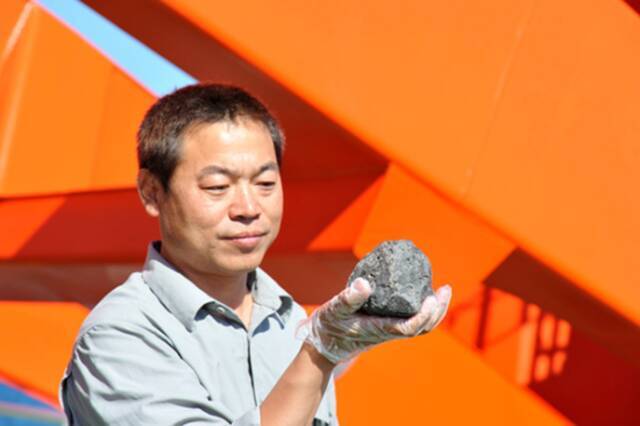  2014年3月20日，中国第30次南极科学考察队格罗夫山队队长缪秉魁展示本次考察中收集的最大一块南极陨石。图