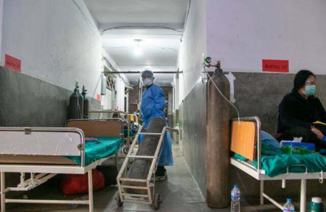 在尼泊尔，一名新冠患者在医院病房外吸氧。