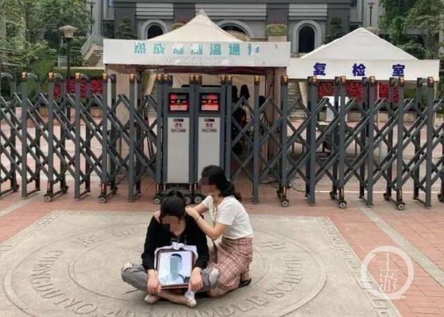 ▲坠楼学生母亲鲁女士在校门口。图片来源/受访者供图