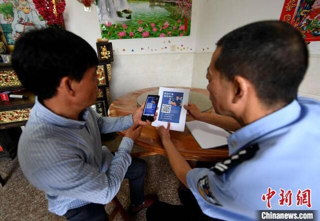 图为挂村民警引导村民扫码注册“金钟罩”反诈骗预警系统。王东明摄