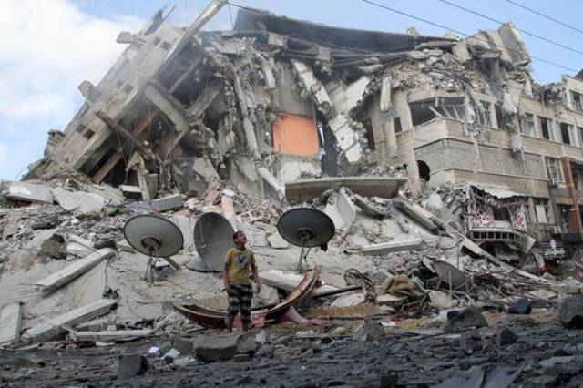 当地时间5月13日，一名巴勒斯坦男孩查看以军空袭造成的破坏情况。新华社图