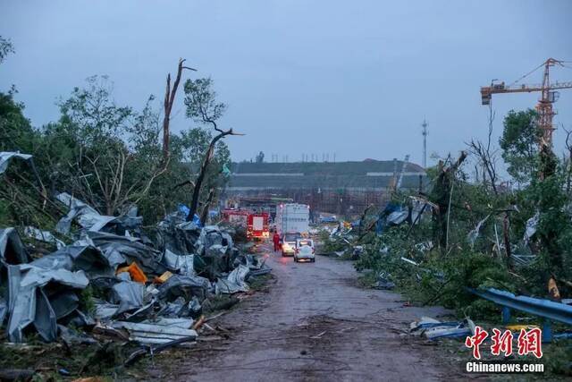 图为道路两侧吹翻的工棚和散落的门窗，路边不少粗壮的大树或被拦腰斩断或被连根拔起。张畅摄