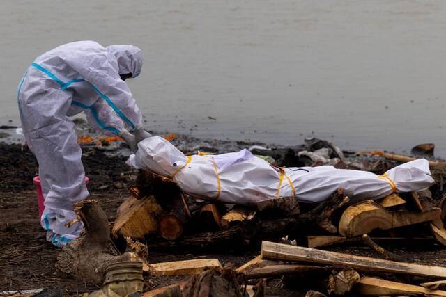 身着防护服男子在恒河岸边拖行尸体图源：外媒