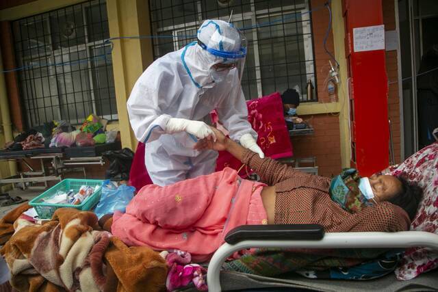 当地时间2021年5月10日，尼泊尔加德满都，医护人员照顾病房外的患者。/IC photo